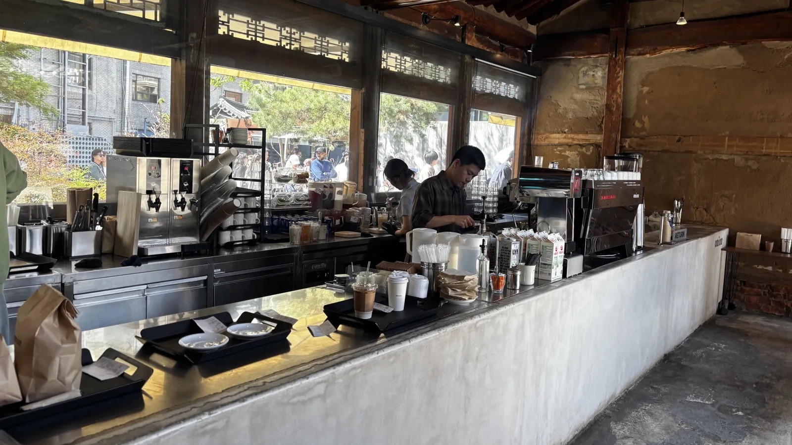 onion安国店のバーカウンター。古い木の梁と土壁、コンクリートのカウンター