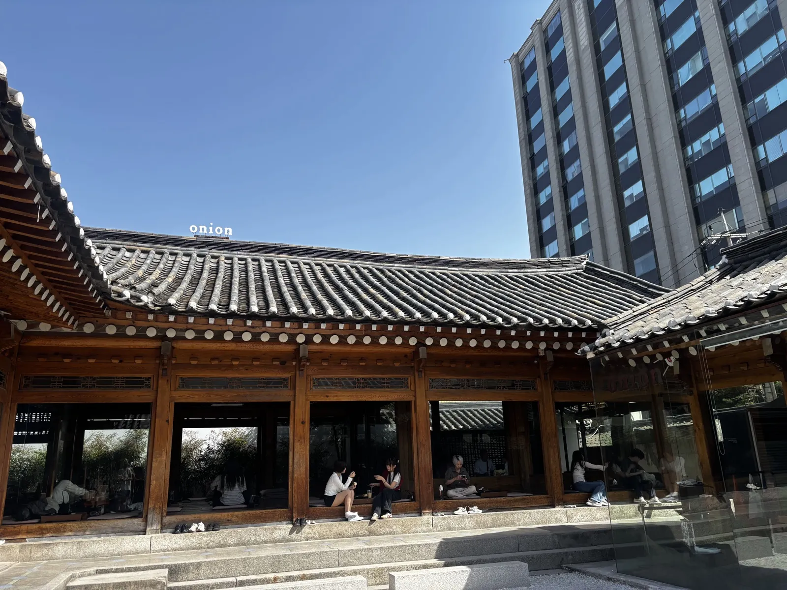 韓屋の瓦屋根とonionの看板、奥に見える高層ビル