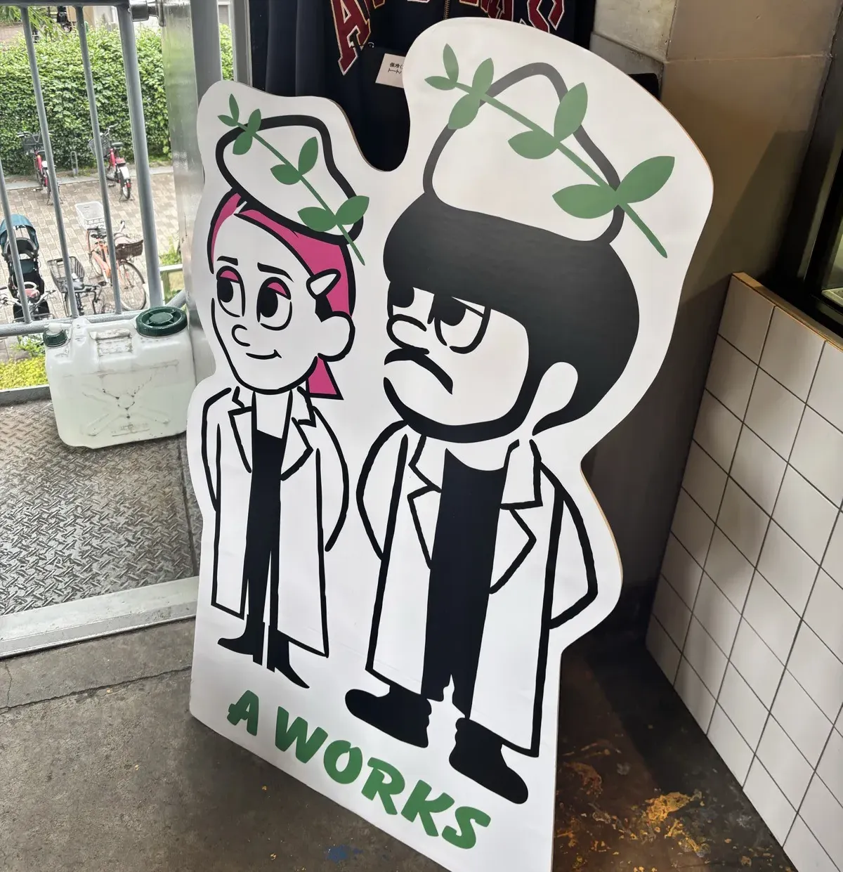 A WORKS の入口に置かれたキャラクターパネルとオリジナルパーカー