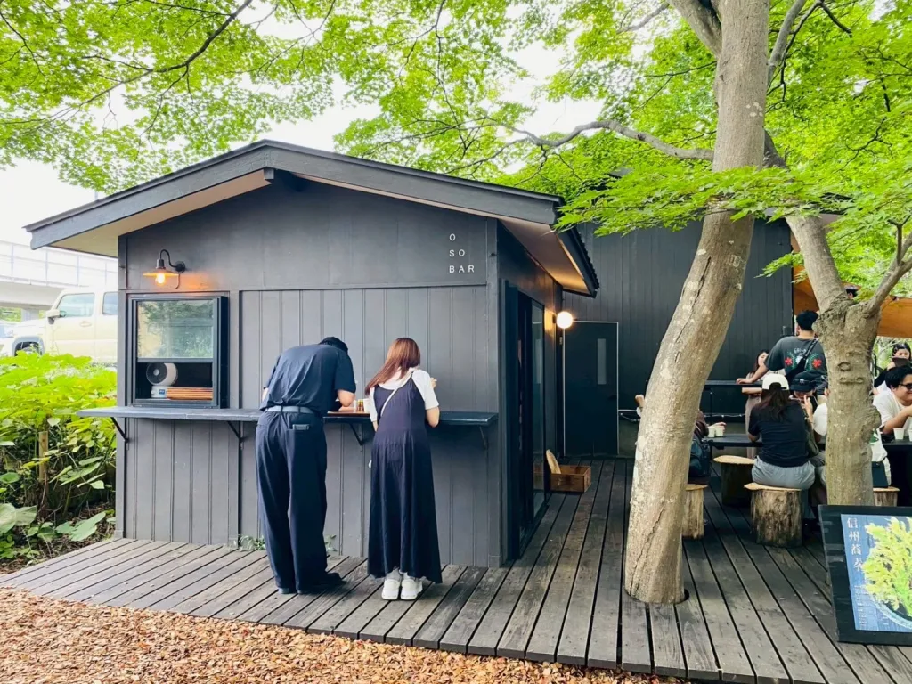 軽井沢コモングラウンズにあるOSOBARの外観と屋外テラス席