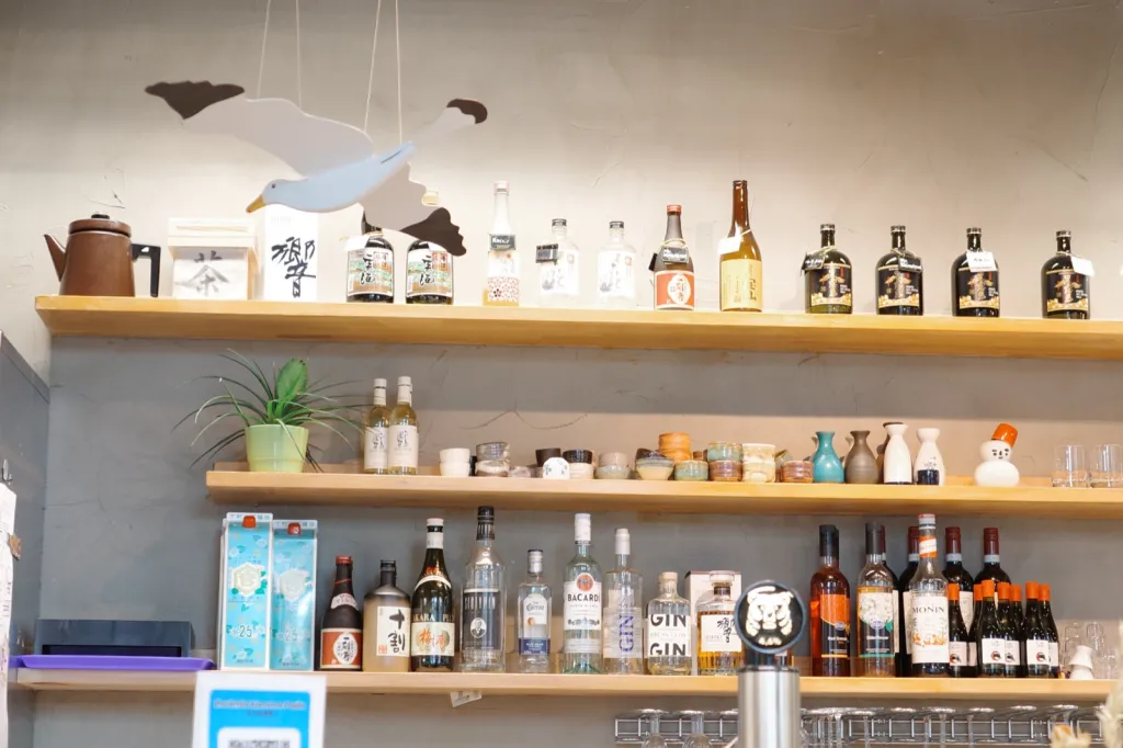 日本酒やウイスキーの瓶とカモメのモビールが飾られた Ravintola Kamome の棚