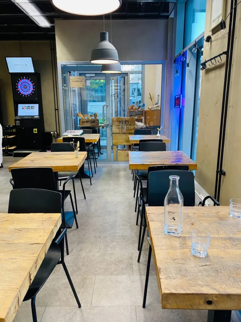 木のテーブルが並ぶ Ravintola Kamome の店内とダーツ台